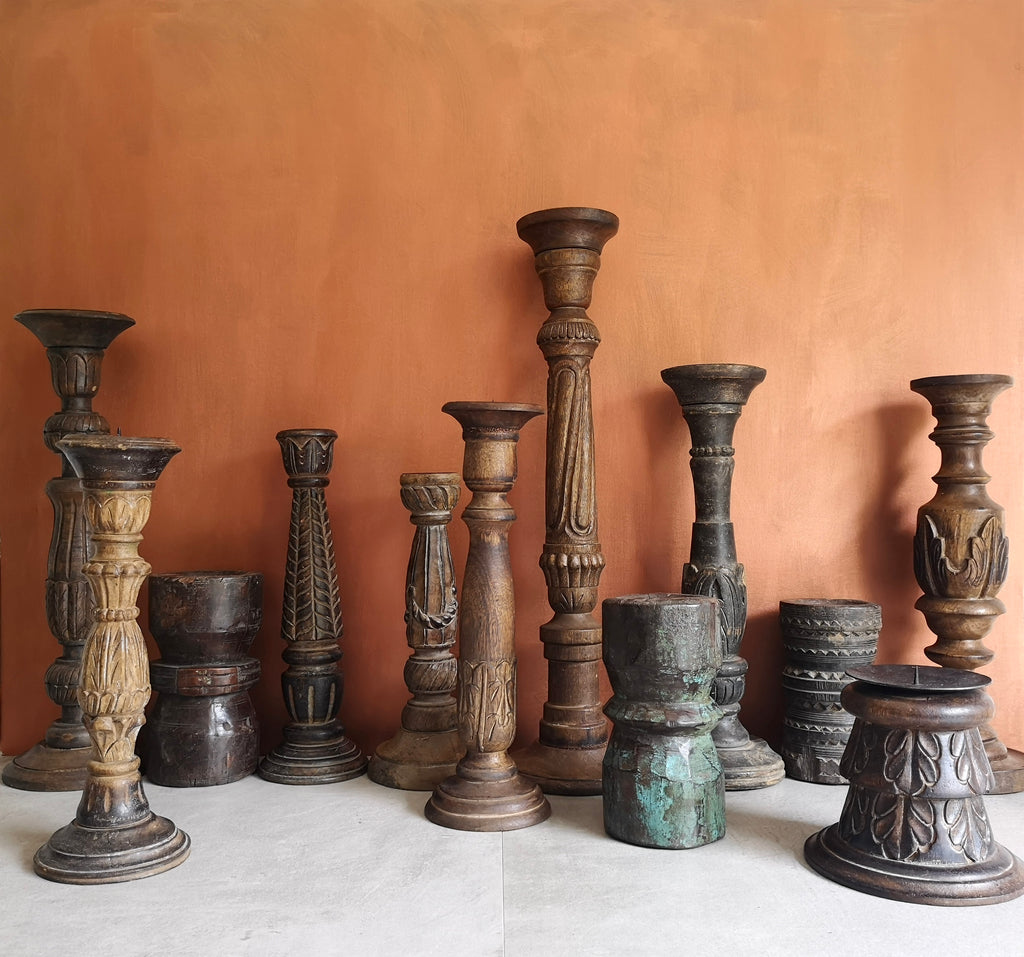 43Collective's collection of antique wooden decorative candle holders in a different shapes and sizes, clustered together against a terracotta background