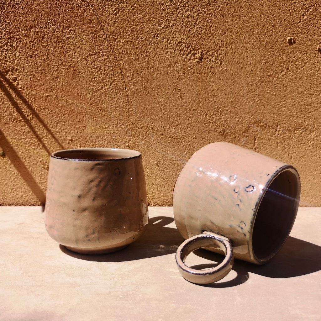 Mugs collection showcasing two handmade rose stoneware mugs against a terracotta background