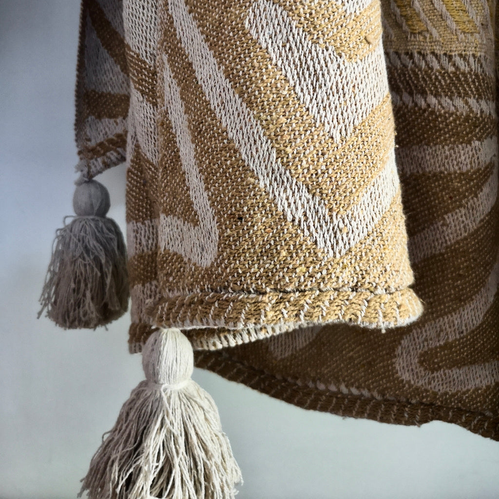 Throws and blankets collection showcasing a jacquard recycled throw in yellow with an ivory pattern and tassels